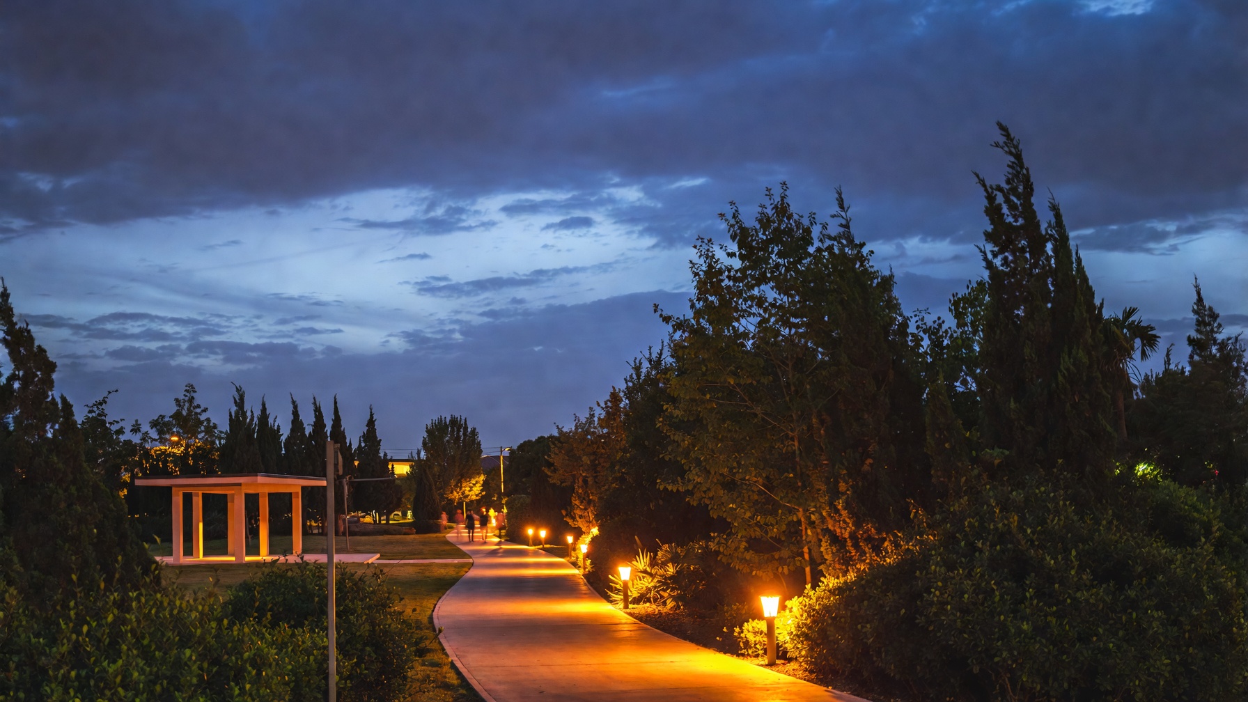 Dusk path through a new neighborhood green with warm landscape lighting